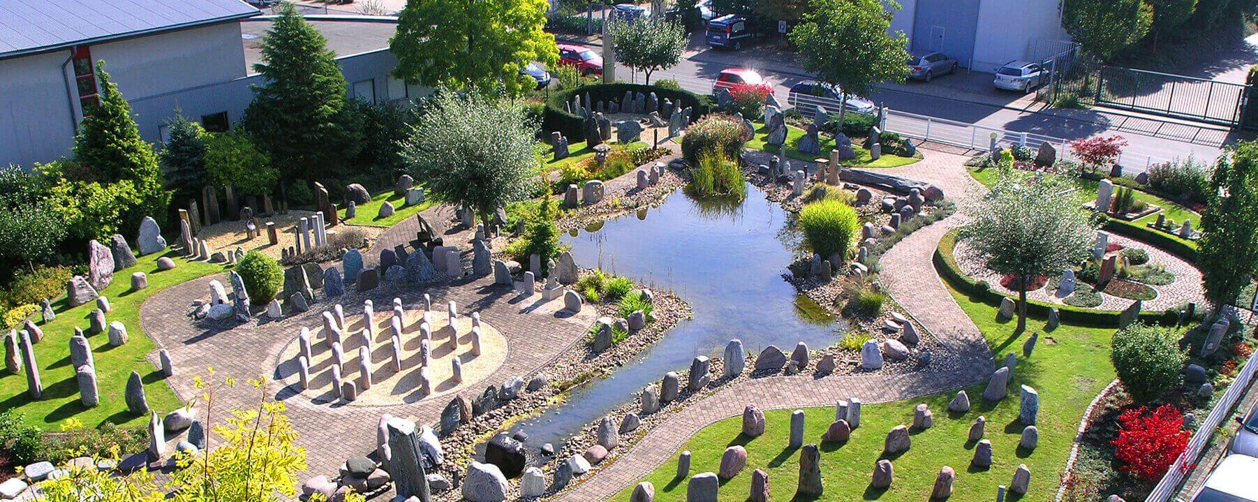 Findlingspark mit Grabmalen und einem Teich